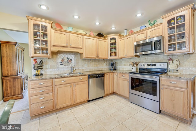 kitchen featuring light brown cabinetry, glass insert cabinets, appliances with stainless steel finishes, and a sink