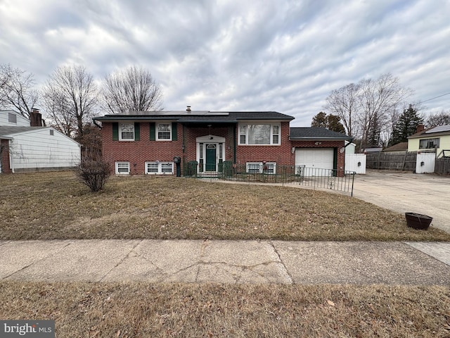 raised ranch with an attached garage, a front yard, concrete driveway, and brick siding