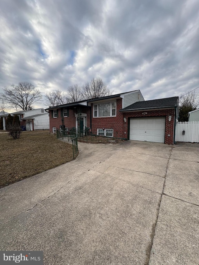 view of front of property featuring an attached garage, driveway, fence, and brick siding