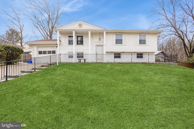 split foyer home with a garage, fence, and a front lawn