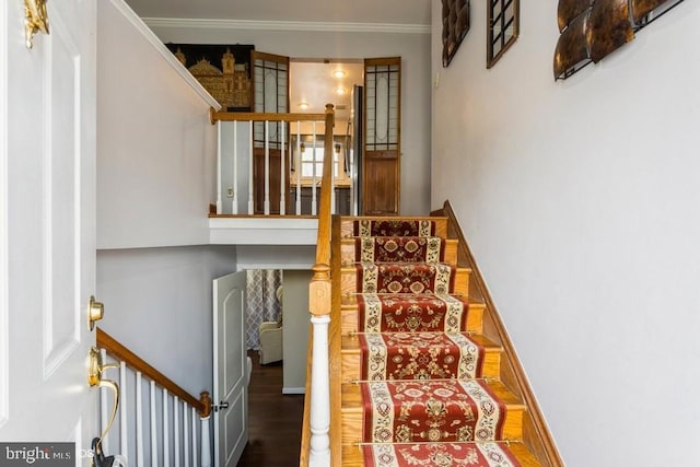 staircase featuring ornamental molding, baseboards, and wood finished floors