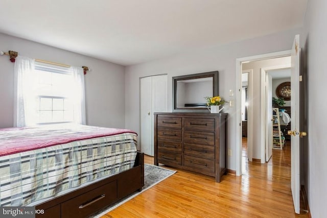 bedroom with light wood-style floors, a closet, and baseboards