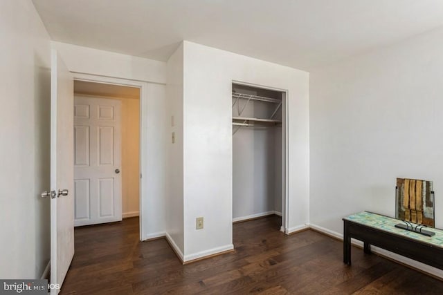 bedroom with dark wood-type flooring, a closet, and baseboards