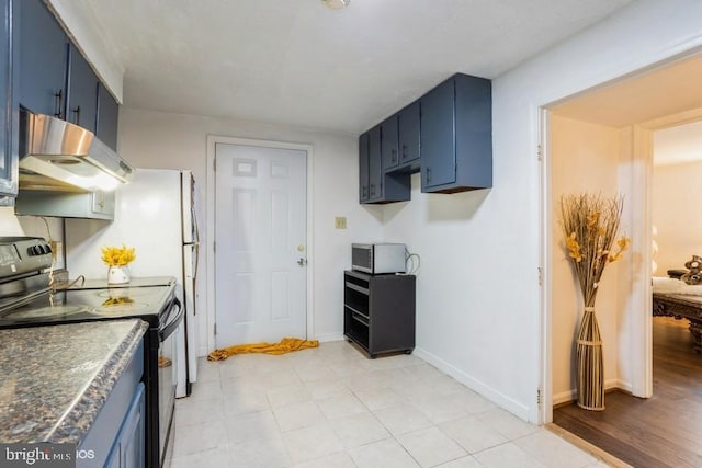 kitchen with black / electric stove, dark countertops, blue cabinets, under cabinet range hood, and baseboards