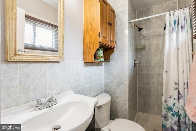 bathroom with tile walls, a sink, a shower stall, and toilet