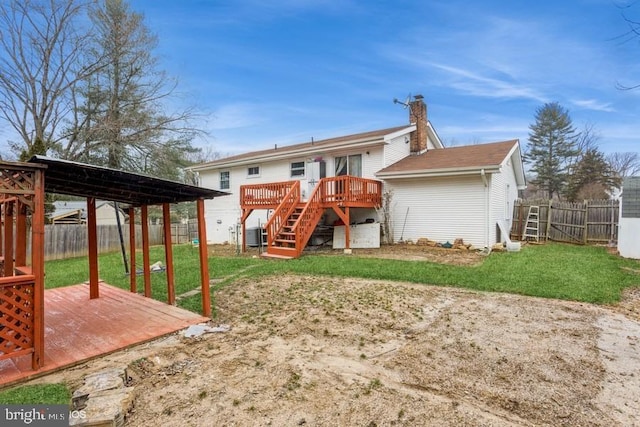 rear view of house featuring a fenced backyard, a yard, a chimney, and a wooden deck