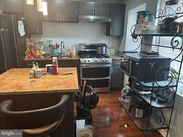 kitchen featuring gray cabinetry, dark wood-type flooring, a sink, double oven range, and under cabinet range hood