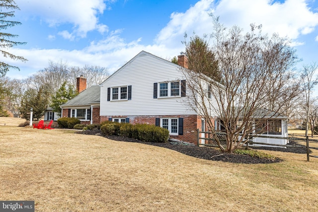 view of front of home with a front yard, brick siding, and a chimney