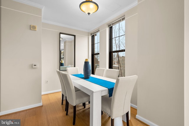 dining room featuring ornamental molding, wood finished floors, and baseboards