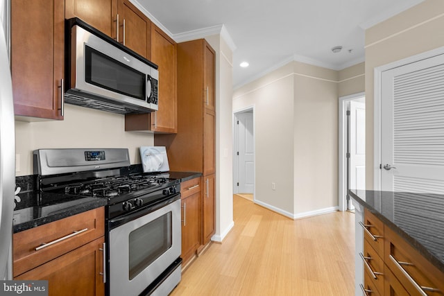 kitchen with stainless steel appliances, dark stone counters, brown cabinetry, and ornamental molding