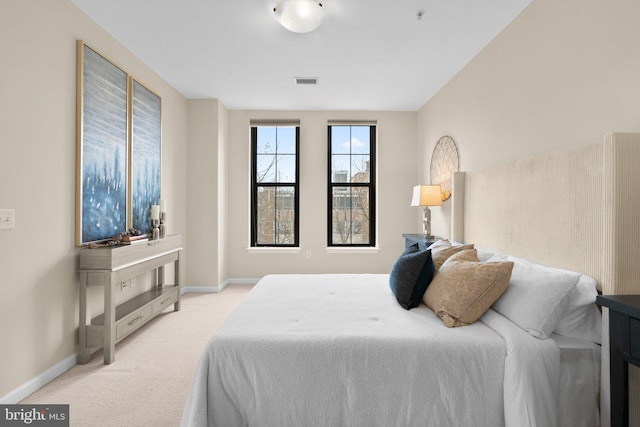 bedroom with light carpet, visible vents, and baseboards