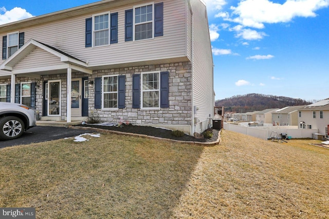 view of front of home featuring stone siding, a front lawn, fence, and a mountain view