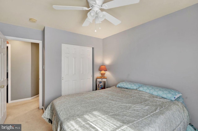 bedroom with light carpet, a ceiling fan, baseboards, and a closet