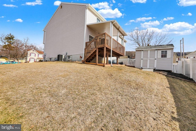 rear view of property featuring an outdoor structure, fence, a yard, stairway, and a storage unit