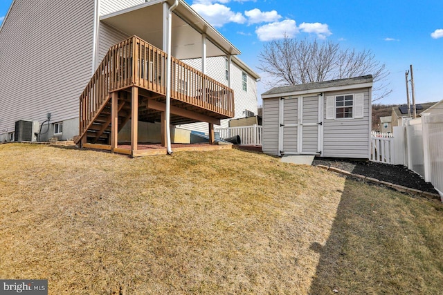 back of property with a lawn, fence, a shed, an outdoor structure, and a wooden deck