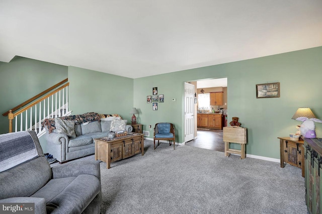 living area featuring baseboards, stairway, and light colored carpet