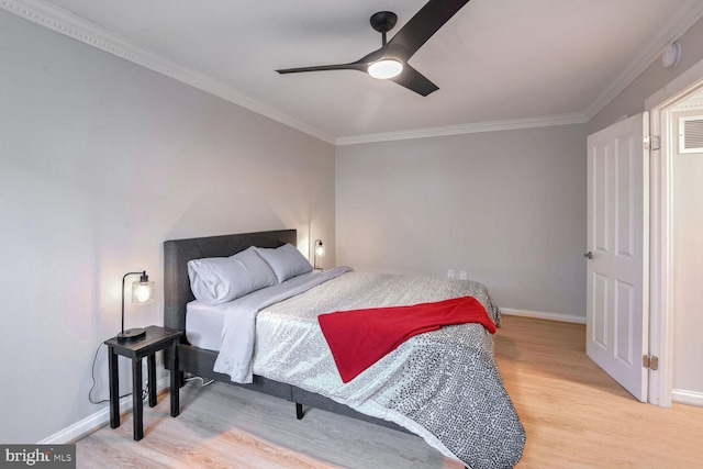 bedroom with light wood-type flooring, crown molding, and baseboards