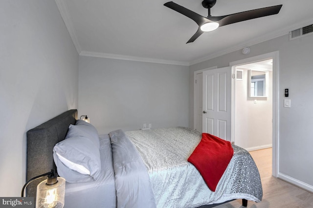 bedroom with a ceiling fan, visible vents, baseboards, ornamental molding, and light wood finished floors