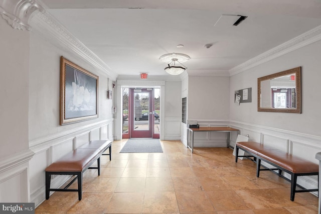 interior space featuring a decorative wall, wainscoting, and crown molding