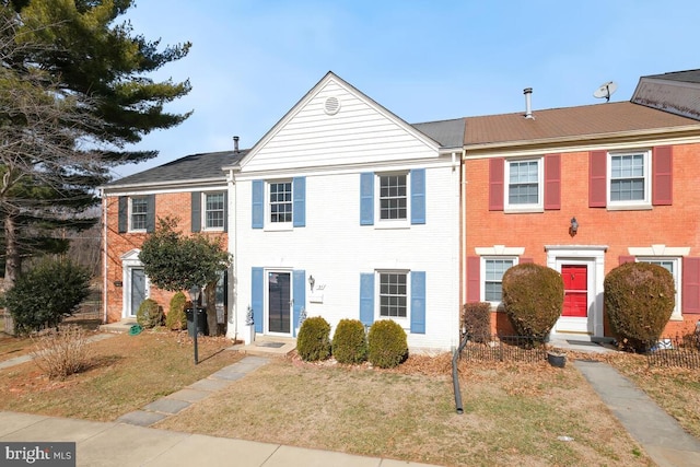 townhome / multi-family property featuring entry steps, brick siding, and a front yard