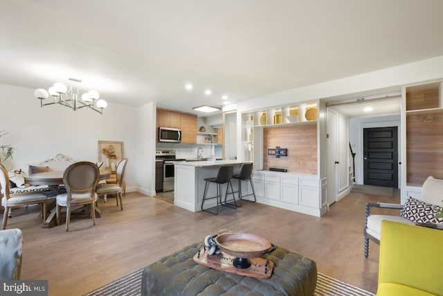 living room with light wood-style flooring, a notable chandelier, and recessed lighting