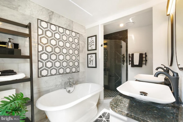 bathroom featuring a sink, a shower stall, tile walls, and a freestanding bath