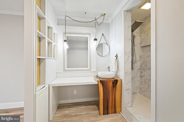 full bath with crown molding, a tile shower, baseboards, and wood finished floors