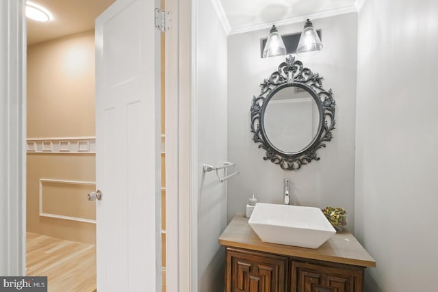 bathroom with wood finished floors, vanity, and crown molding