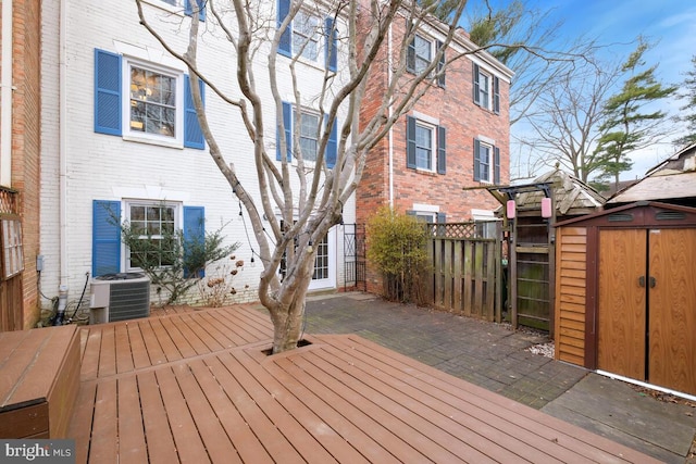 wooden terrace with a storage shed, fence, central AC, and an outbuilding