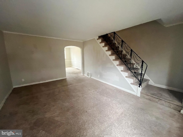 unfurnished living room with stairway, visible vents, arched walkways, and baseboards