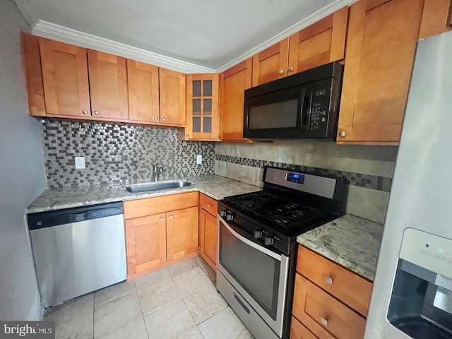 kitchen featuring brown cabinetry, glass insert cabinets, appliances with stainless steel finishes, light stone counters, and a sink