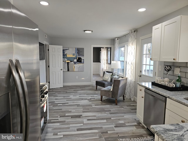kitchen with appliances with stainless steel finishes, recessed lighting, white cabinets, and light stone counters