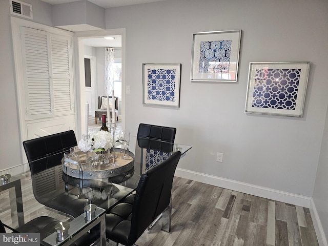 dining area featuring wood finished floors, visible vents, and baseboards