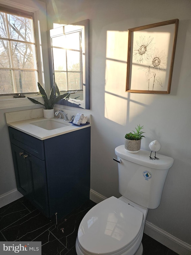bathroom with marble finish floor, vanity, toilet, and baseboards