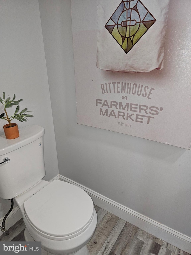 bathroom with toilet, baseboards, and wood finished floors