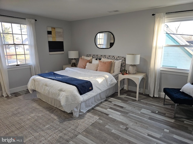 bedroom with wood finished floors, visible vents, and baseboards