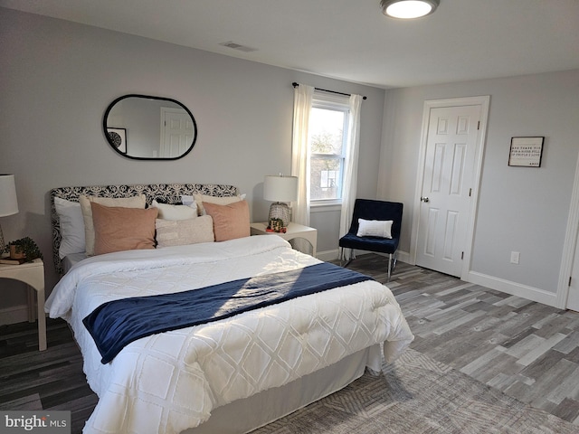 bedroom with wood finished floors, visible vents, and baseboards