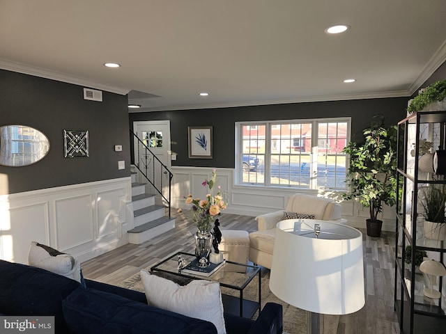 living room featuring a decorative wall, stairway, wood finished floors, and crown molding