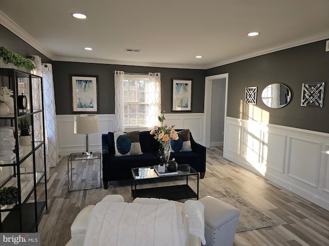 living room with visible vents, crown molding, and wood finished floors