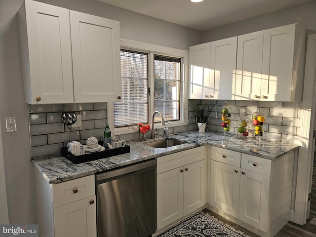 kitchen with decorative backsplash, white cabinets, dishwasher, light stone counters, and a sink
