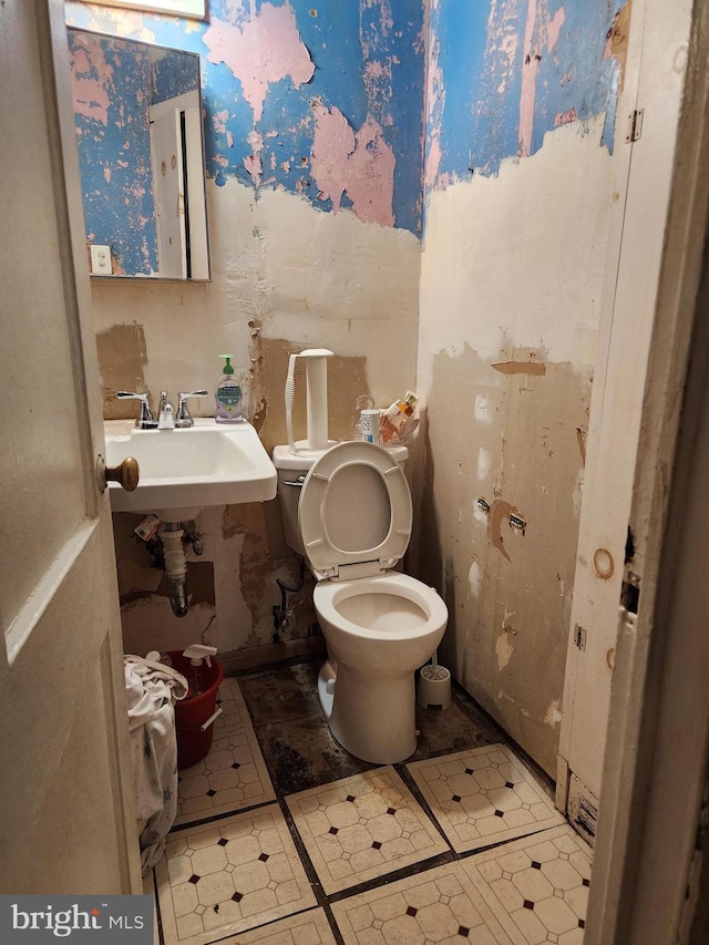 half bath with tile patterned floors, toilet, and wallpapered walls