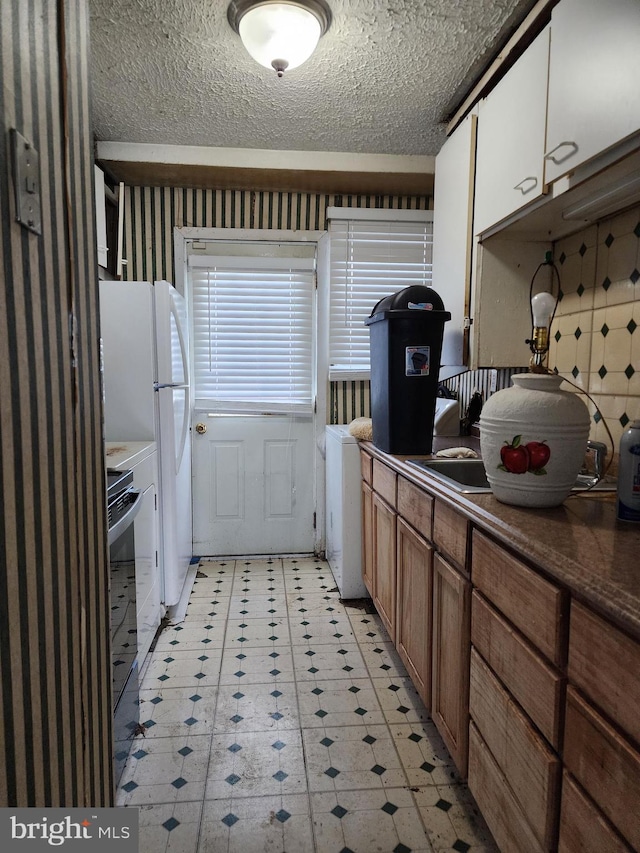 kitchen featuring dark countertops, stove, brown cabinets, a textured ceiling, and light floors