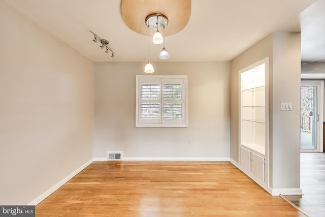 unfurnished dining area featuring baseboards, visible vents, and light wood finished floors