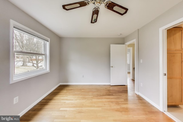 unfurnished bedroom with light wood-type flooring, a ceiling fan, and baseboards