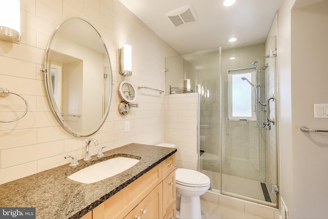 bathroom featuring toilet, vanity, visible vents, tile walls, and a shower stall