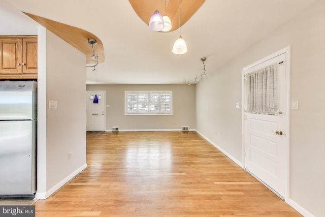 interior space featuring light wood-style floors, visible vents, and baseboards