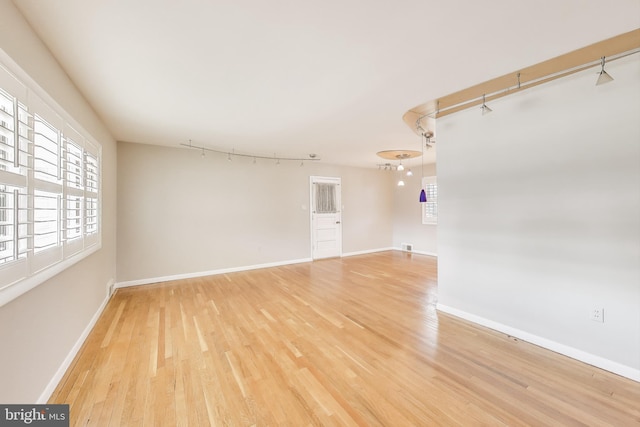 unfurnished room featuring light wood-style floors, baseboards, and track lighting