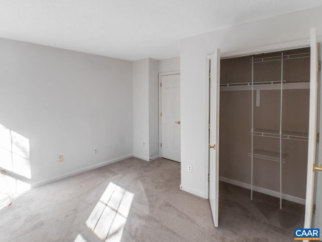 unfurnished bedroom featuring light carpet, a closet, and baseboards