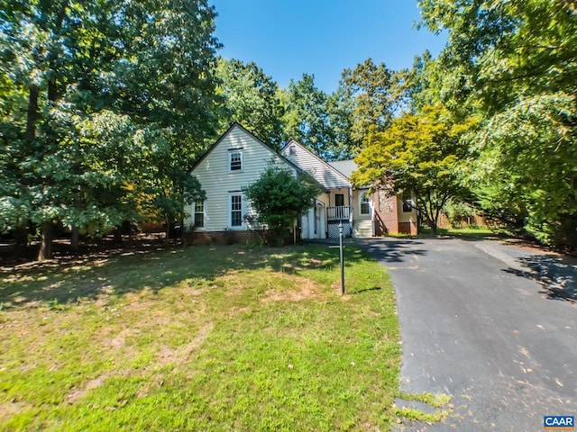 view of front of house with driveway, brick siding, and a front yard