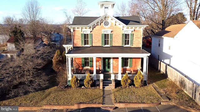 italianate house featuring covered porch and fence